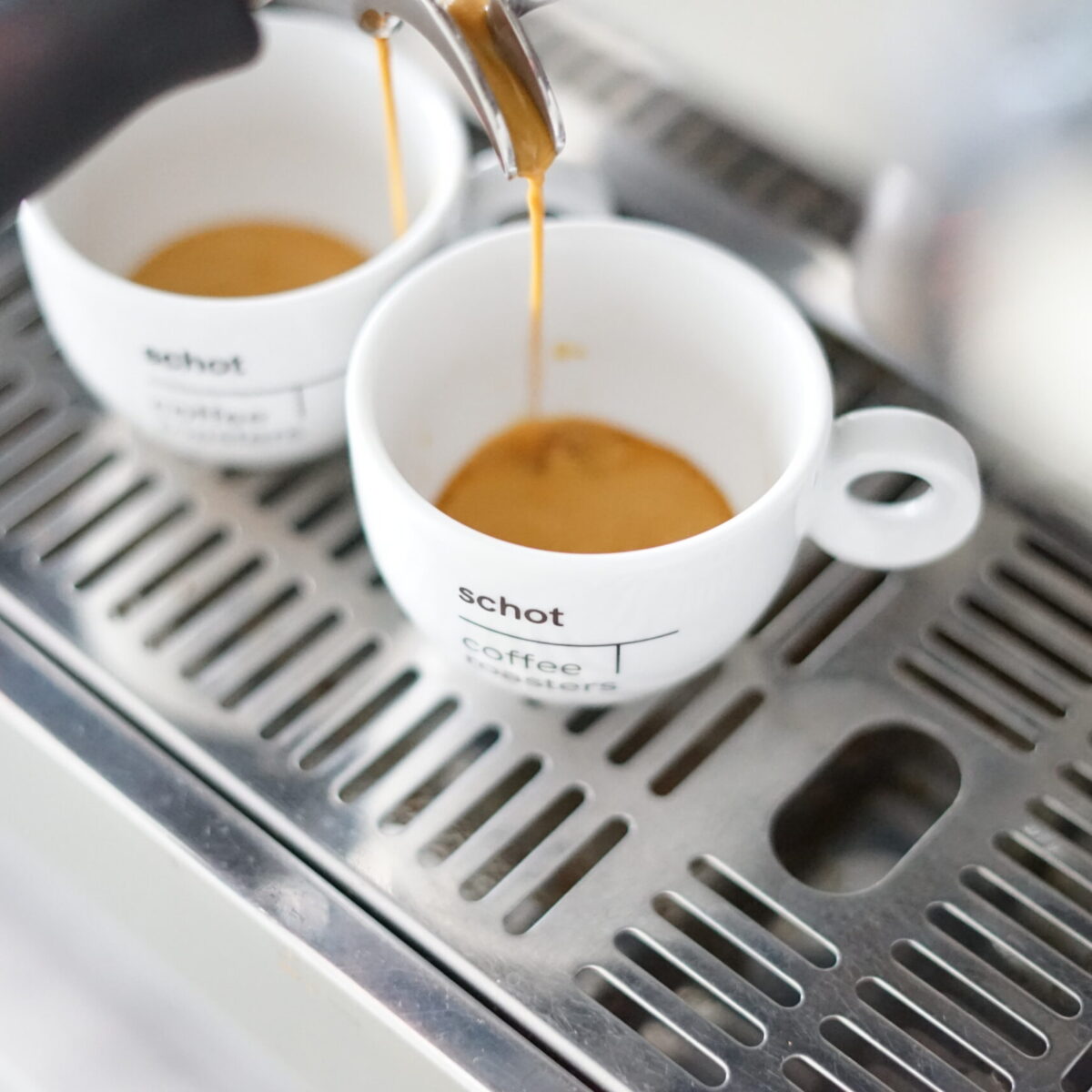 Schot koffiekopjes onder een espressomachine